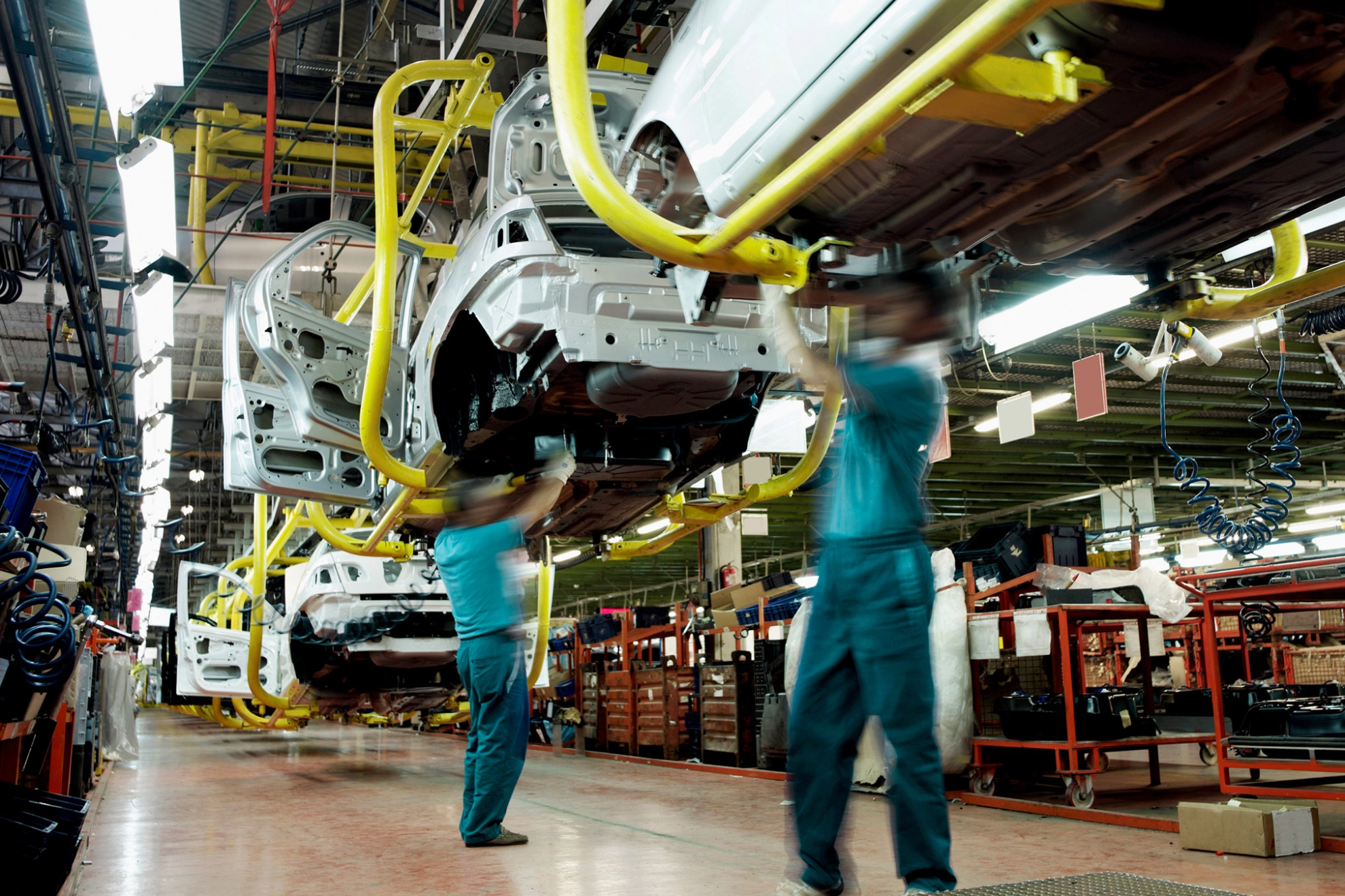 Zwei Männer arbeiten an Karosserien in einer Autofabrik.