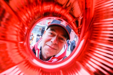 Ein Mann mit IG Metall-Kappe schaut durch einen runden Luftballon.